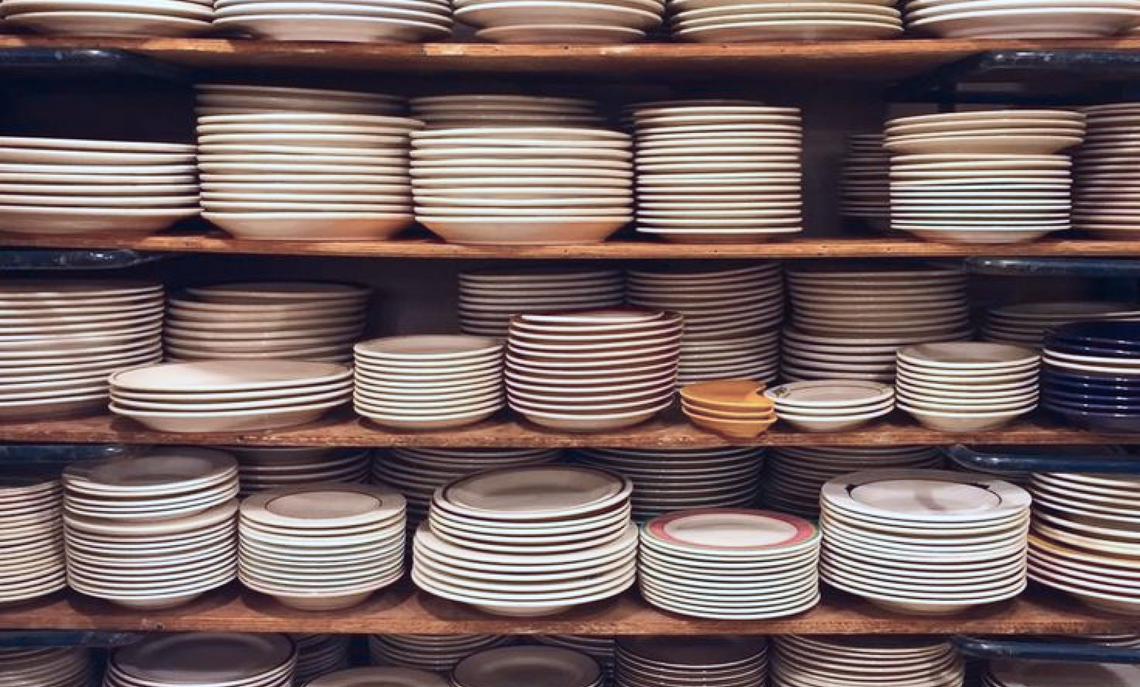Shelves filled with stacked ceramic plates in a warehouse setting